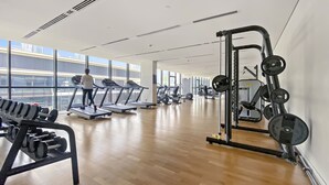 Une salle de sport équipée de tapis de course, d’appareils de musculation et de poids libres.