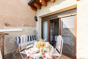 Enjoy meals al fresco in this charming outdoor dining area with a round table, comfortable chairs, and a cozy lamp.
