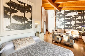 Relax in a stylish space with a large bed, seating area, and artwork of trees.