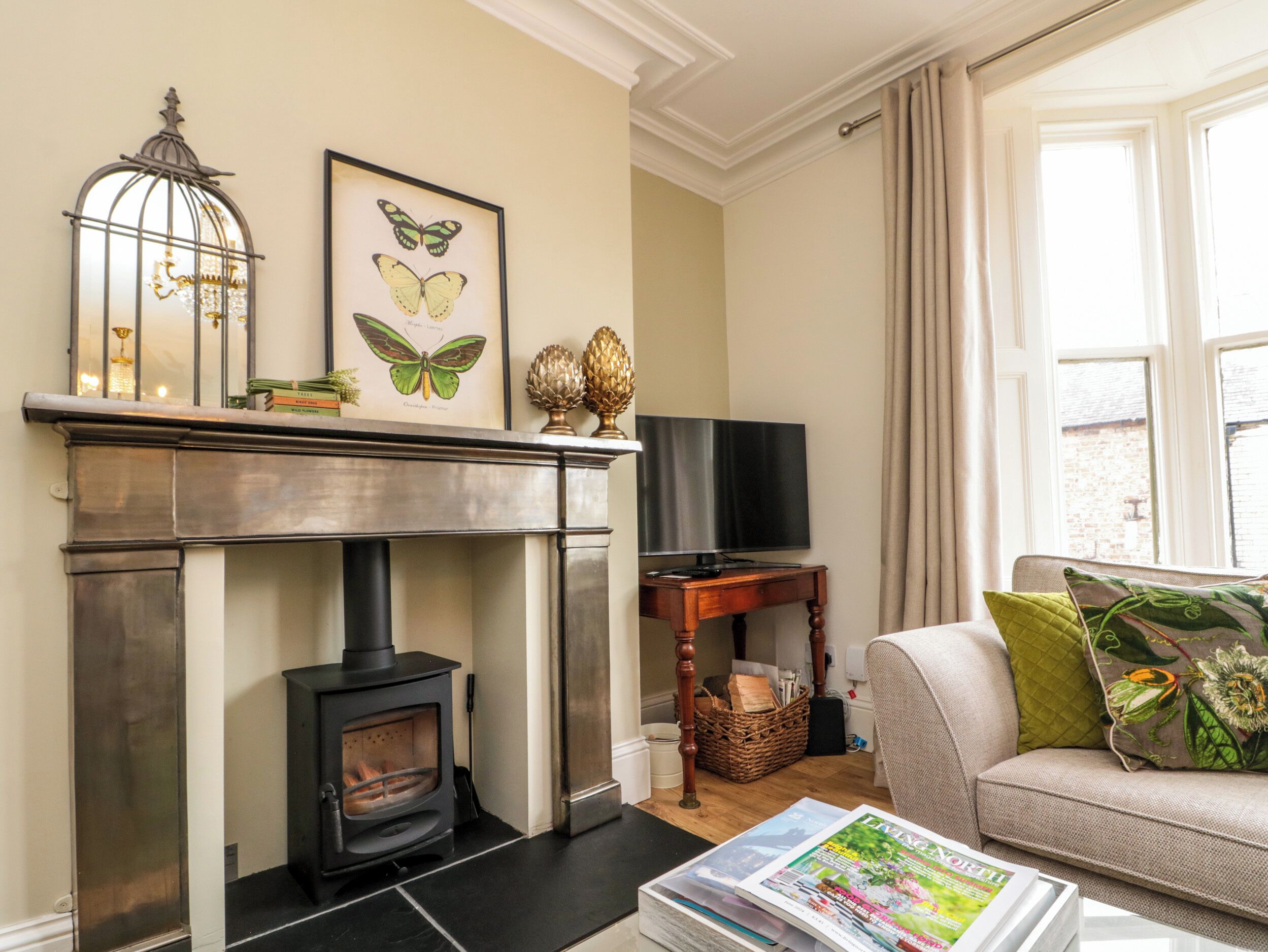 Una sala de estar con chimenea, televisor y sofá con cojines.