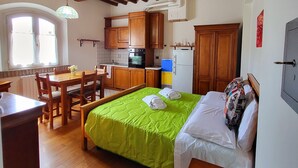 A compact room with a bed, a dining table, and a kitchenette. - Studio Apartment B4 (Modena)