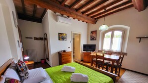 A hotel room with a bed, a desk, a chair, a television, and a window. - Studio Apartment B4 (Modena)