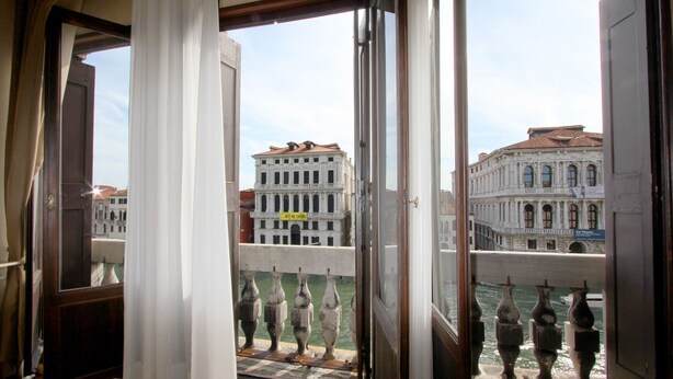 Una habitación con un amplio ventanal que da a un edificio histórico y un canal.