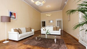 Un salón amplio con dos sofás blancos, una mesa de centro de cristal y una planta grande.