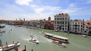 Un canal con barcos y un autobús acuático, rodeado de edificios históricos.