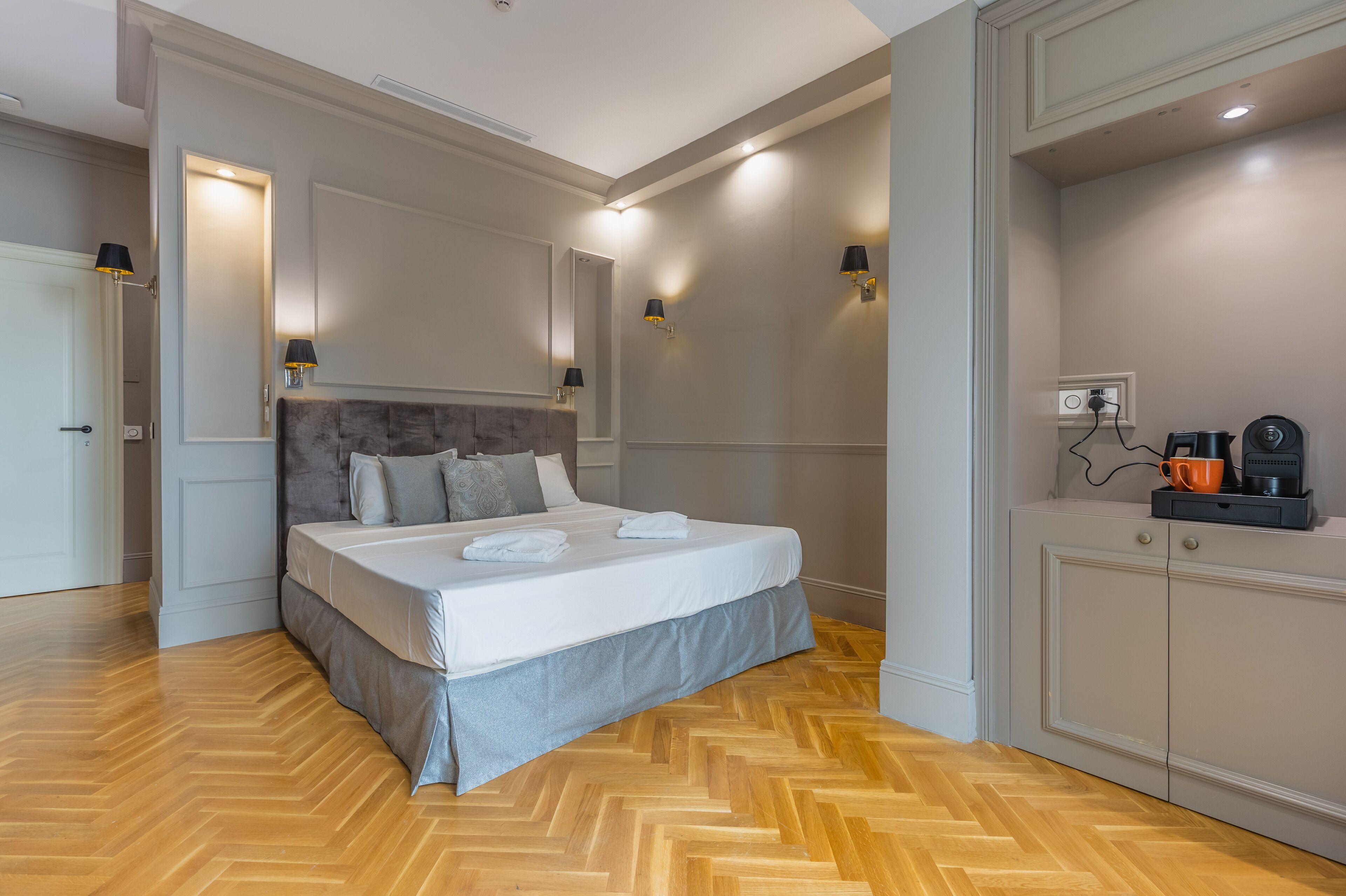 Un dormitorio con cama, lámparas de noche, un armario y una cafetera.