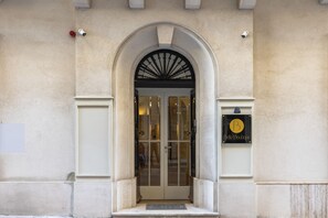An arched entrance with a glass door, a sign with a 'B' logo, and a small step leading up to the door. - Belle Boutique (Sliema)