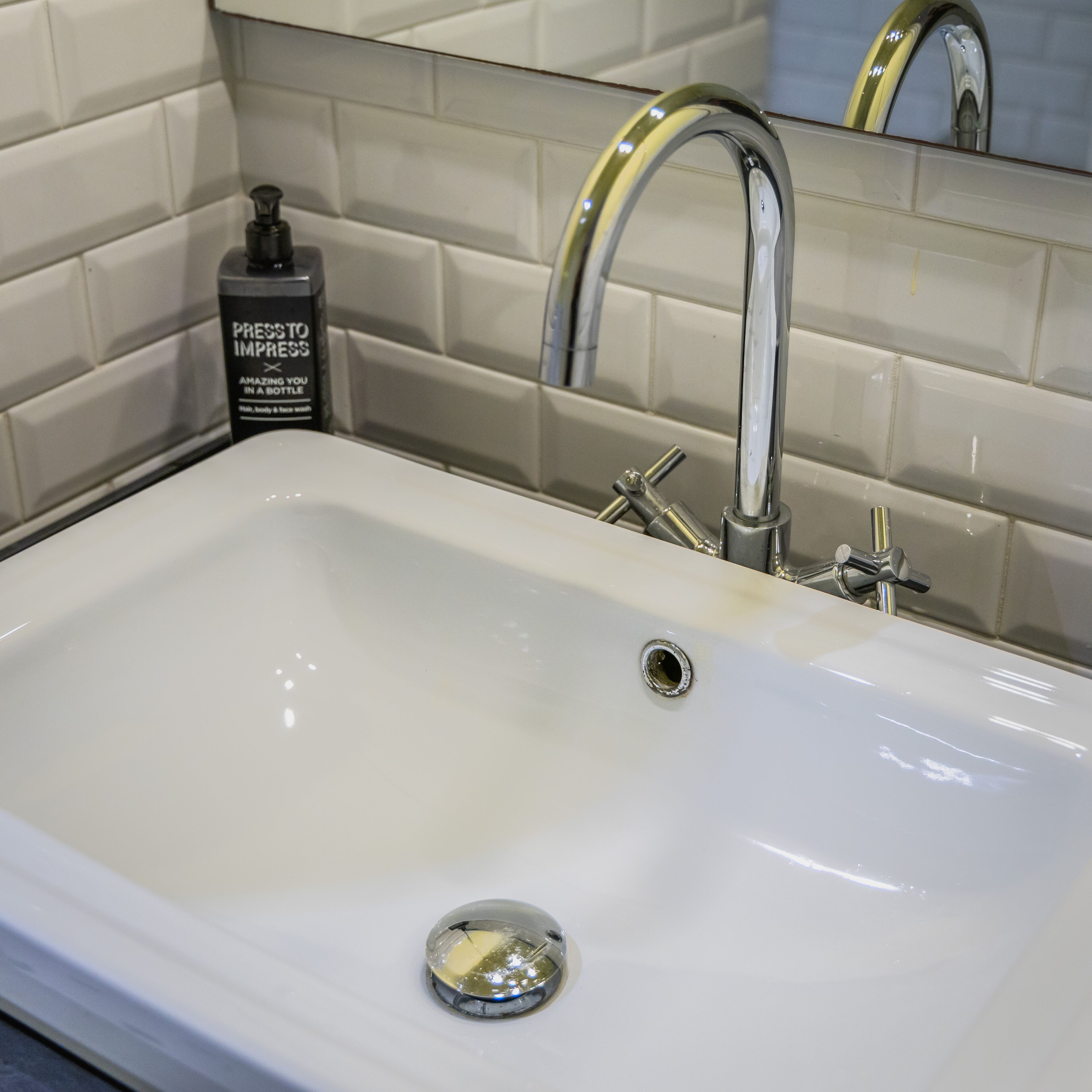 A white bathroom sink with a modern faucet and a soap dispenser.