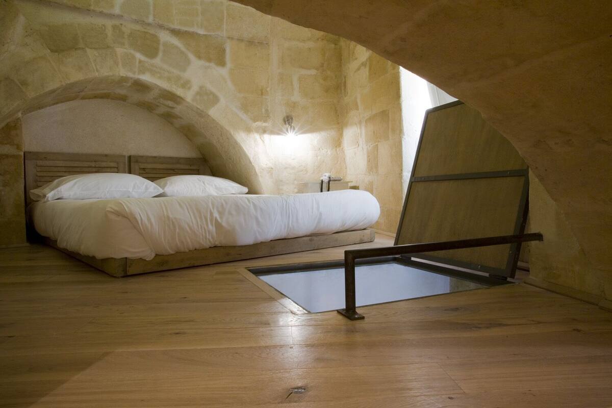 A bedroom with a stone wall, a bed, and a skylight.