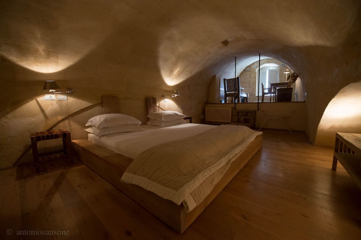 A cozy attic bedroom with a wooden bed, two bedside tables, and a mirror.