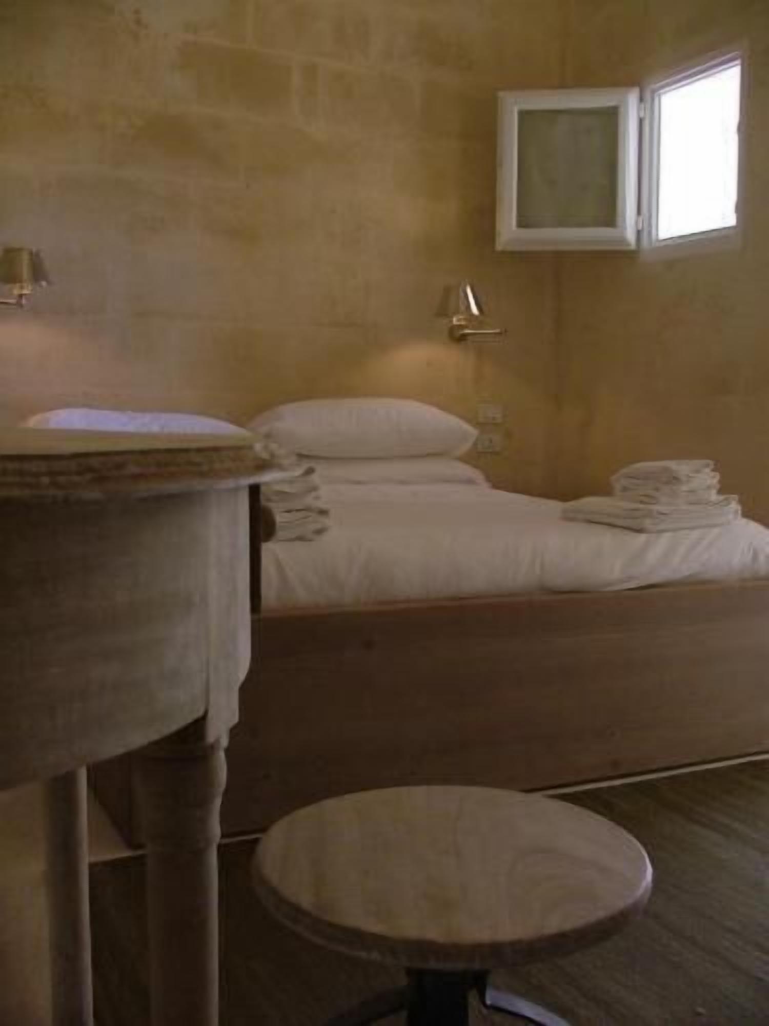 A room with a bed, a round table, and a small stool.