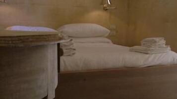 A room with a bed, a round table, and a small stool.