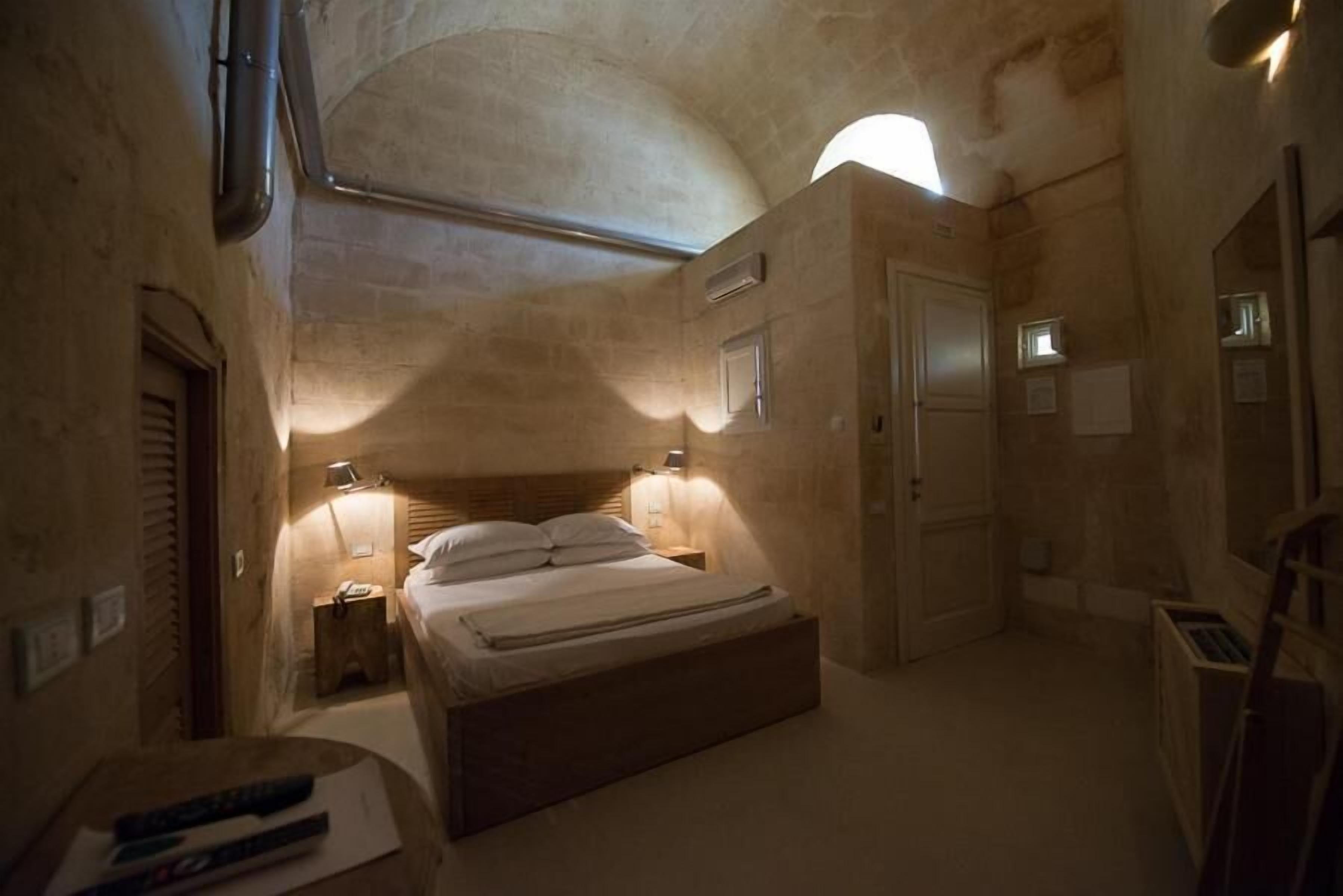 Ein schwach beleuchtetes Schlafzimmer mit einem Einzelbett, einem Nachttisch und einer Lampe.