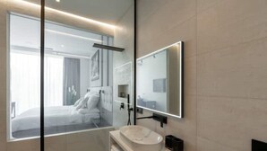 Ein modernes Badezimmer mit einem großen Spiegel, einem runden Waschbecken und einer Duschkabine aus Glas.