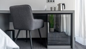 Ein modernes Zimmer mit einem grau bezogenen Sessel, einem Glastisch und einem kleinen Topfpflanzen.