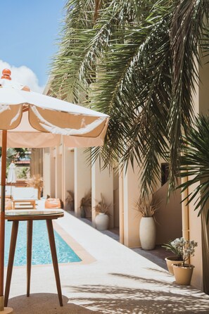 A poolside area with a table and chairs under a canopy, surrounded by palm trees and potted plants. - Casa Solana Patong (Patong)