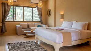A bedroom with a bed, a sofa, a small table, and a window with curtains. - Casa Solana Patong (Patong)