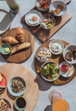 A variety of breakfast items including croissants, eggs, and fruit on wooden boards. - Casa Solana Patong (Patong)