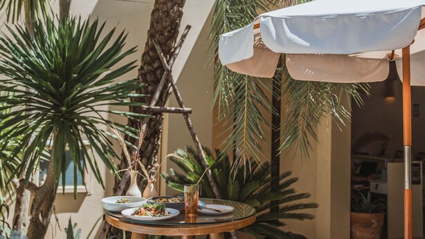 An outdoor dining area with a table and chairs, surrounded by potted plants and a palm tree. - Casa Solana Patong (Patong)