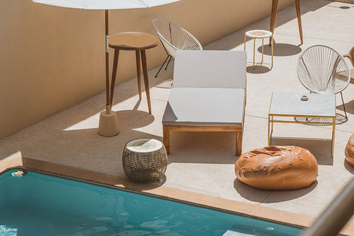 A poolside area with a pool, lounge chairs, a small table, and an umbrella.