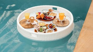 A poolside breakfast setup with a wicker tray, food, and drinks. - Casa Solana Patong (Patong)