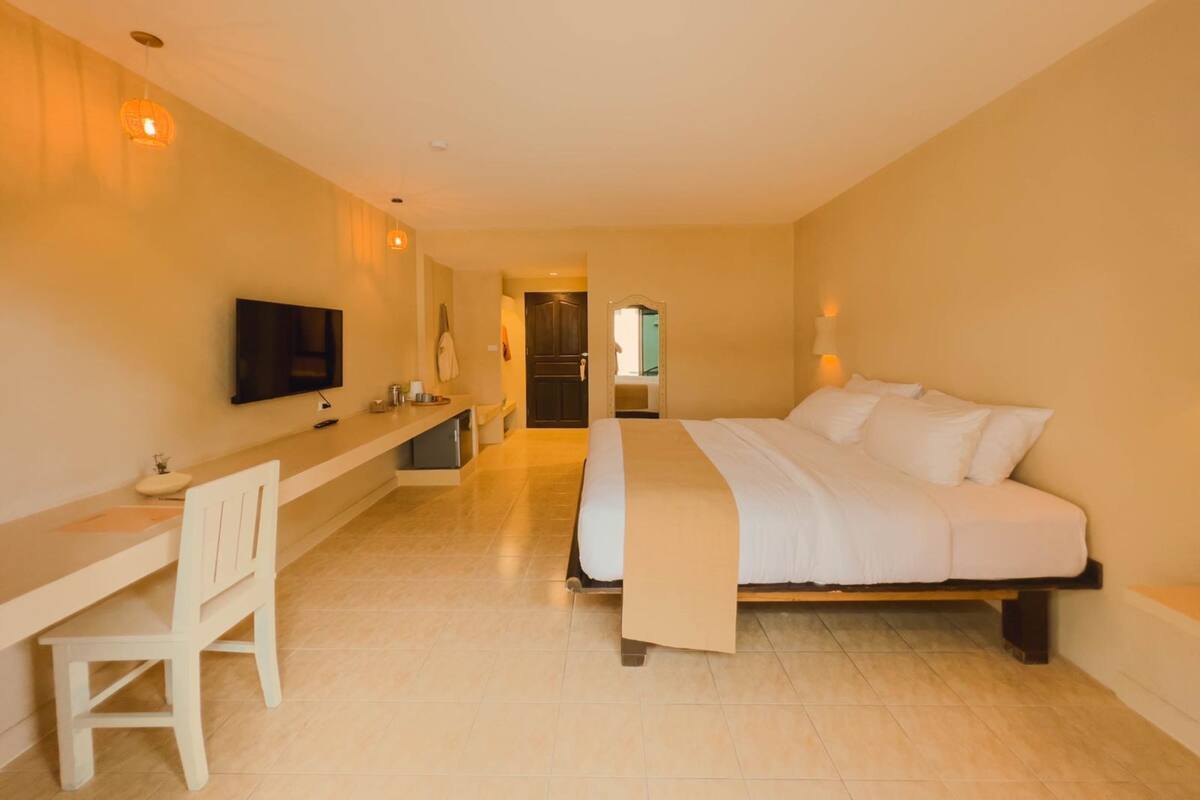 A hotel room with a bed, a desk, a chair, a television, and a mirror.