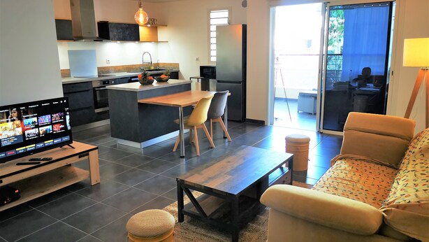 A modern living space with a kitchen, dining area, and seating area. - Appt "corail" au Pied du Lagon de St Leu (Saint-Leu)
