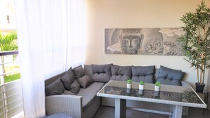 A corner seating area with a sofa and cushions, a glass-top table with potted plants, and a large Buddha artwork on the wall. - Appt "corail" au Pied du Lagon de St Leu (Saint-Leu)