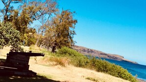 A coastal landscape with a wooden bench, trees, and a clear view of the ocean. - Appt "corail" au Pied du Lagon de St Leu (Saint-Leu)