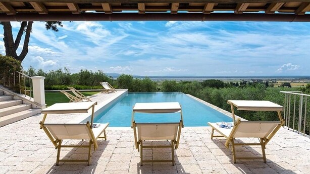 Una piscina con tres tumbonas y vistas al mar.