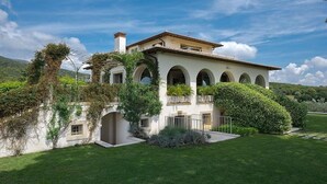 Una villa con fachada blanca, ventanas arqueadas y un balcón.