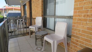 Un balcon avec deux chaises en plastique blanc et une petite table en bois.