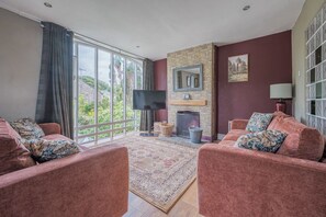 A living room with a fireplace, a television, and a large window with curtains. - Silverdale Cottage Lake District/Lancashire
Two double, one twin (Silverdale)