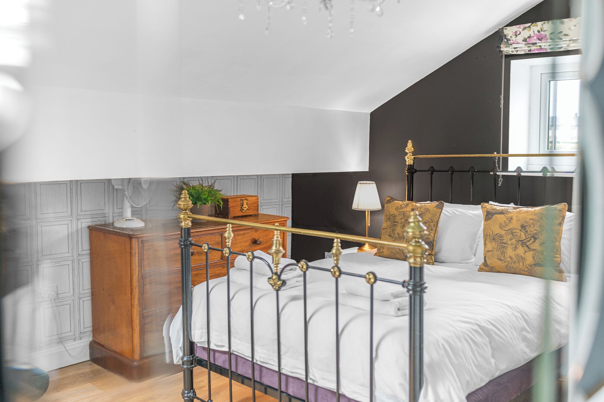 A bedroom with a bed, bedside table, lamp, and a window with curtains.