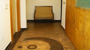 Un pasillo con suelo de madera, un banco y una lámpara de techo circular.