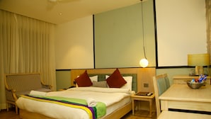 Una habitación de hotel con una cama grande, una silla de madera, un escritorio y una lámpara.