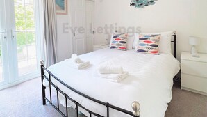 Una camera da letto con un letto, un comodino, una lampada, una luce a soffitto, una finestra con tende e un elemento decorativo a parete.