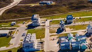 Vista aérea de una zona costera con un conjunto de edificios azules, una carretera y una playa.