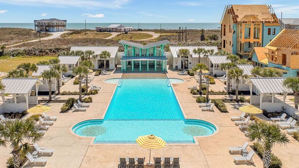 A resort with a central swimming pool, lounge areas, and beach views. - Resort Pools, Golf Cart Boardwalk to the Beach (Port Aransas)