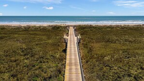 A wooden boardwalk leading to a beach with a clear view of the ocean. - Resort Pools, Golf Cart Boardwalk to the Beach (Port Aransas)
