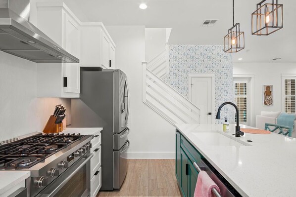 Una cocina moderna con armarios blancos, una estufa de acero inoxidable y un refrigerador empotrado.