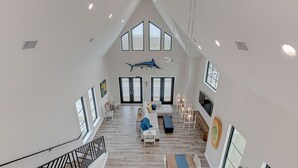 A spacious living area with a high ceiling, large windows, and a modern design.