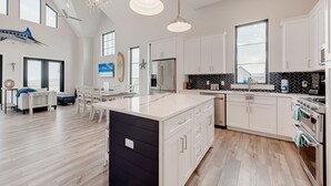 A spacious kitchen with a large island, white cabinetry, and modern appliances.