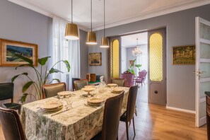 A dining area with a table set for four, surrounded by chairs, with a chandelier and pendant lights above. - Riva House Catania by Wonderful Italy (Catania)
