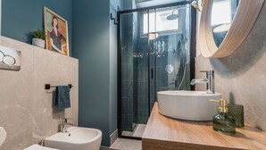 A modern bathroom with a glass shower enclosure, a white sink, and a wooden vanity.