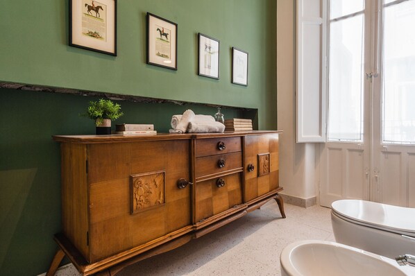 A wooden dresser with drawers, a potted plant, and framed pictures on the wall. - Riva House Catania by Wonderful Italy (Catania)
