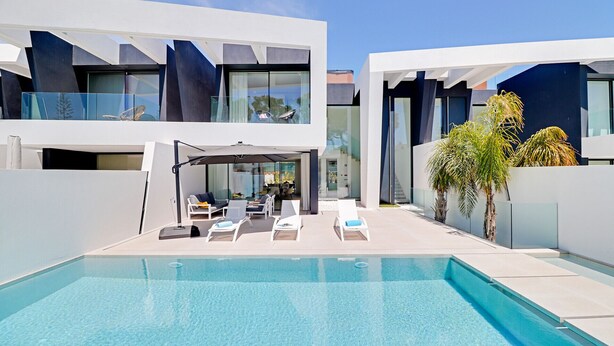 Un espace moderne aménagé au bord de la piscine, avec des chaises longues et un coin salon abrité.