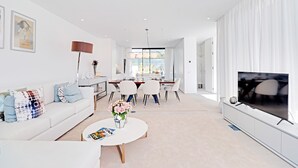 Un salon moderne avec un canapé, une table basse et un téléviseur. Il y a également un coin repas avec des chaises et une table.