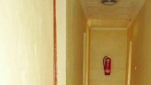 Een smalle, betegelde gang met een brandblusser aan de muur.