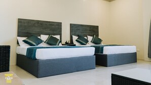 Habitación de hotel con dos camas, cada una con cabecero oscuro y ropa de cama blanca.
